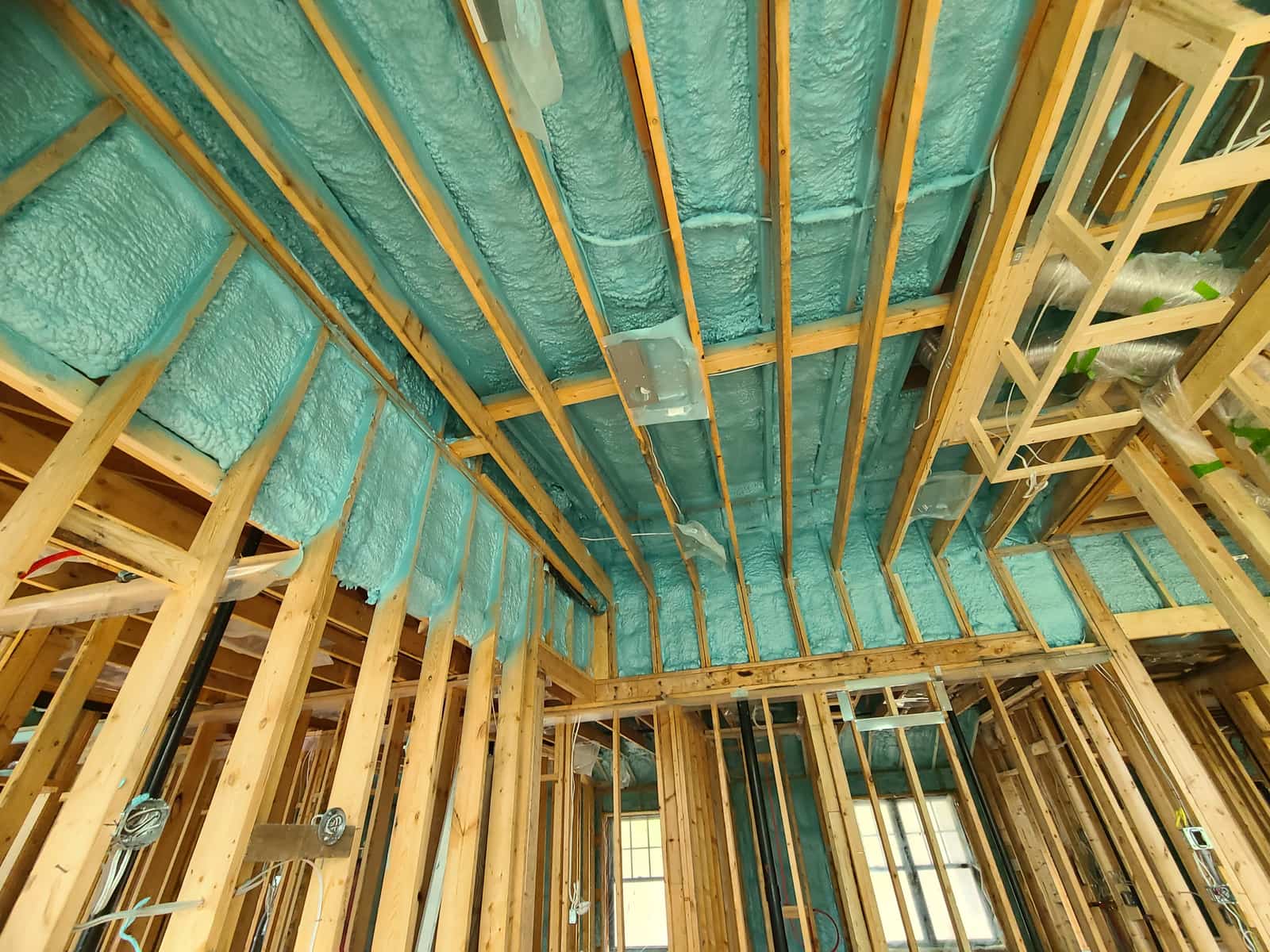 Closed-cell spray foam sprayed between ceiling joists and wall studs on a Fahrenheit Foam job
